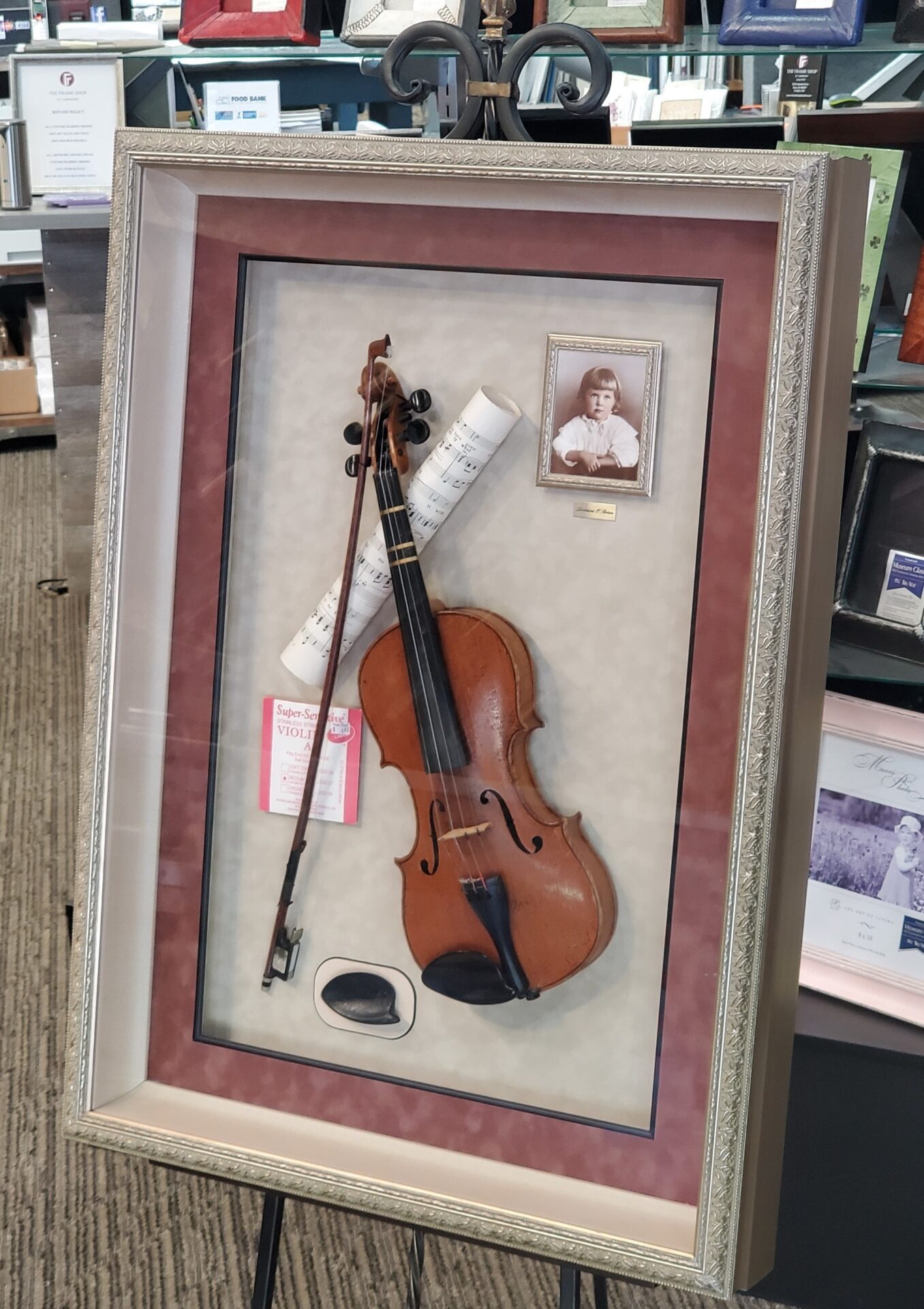 A framed violin with a bow and a picture of the instrument.